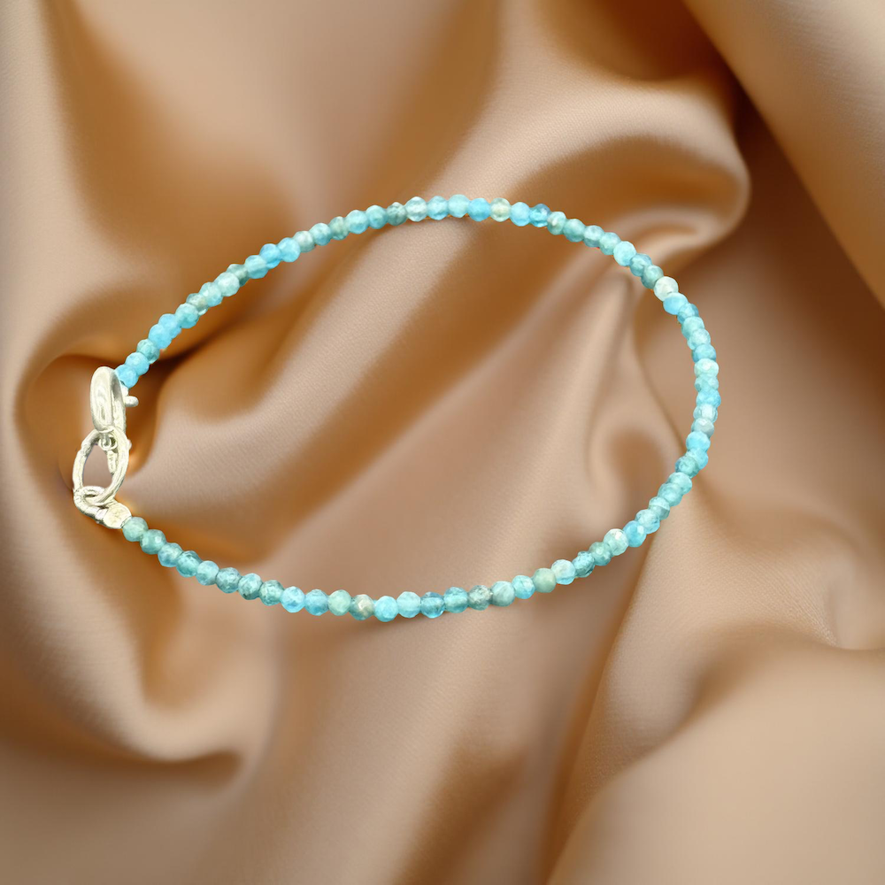 Hellblaues Apatit Armband auf glänzendem, goldenem Seidenstoff