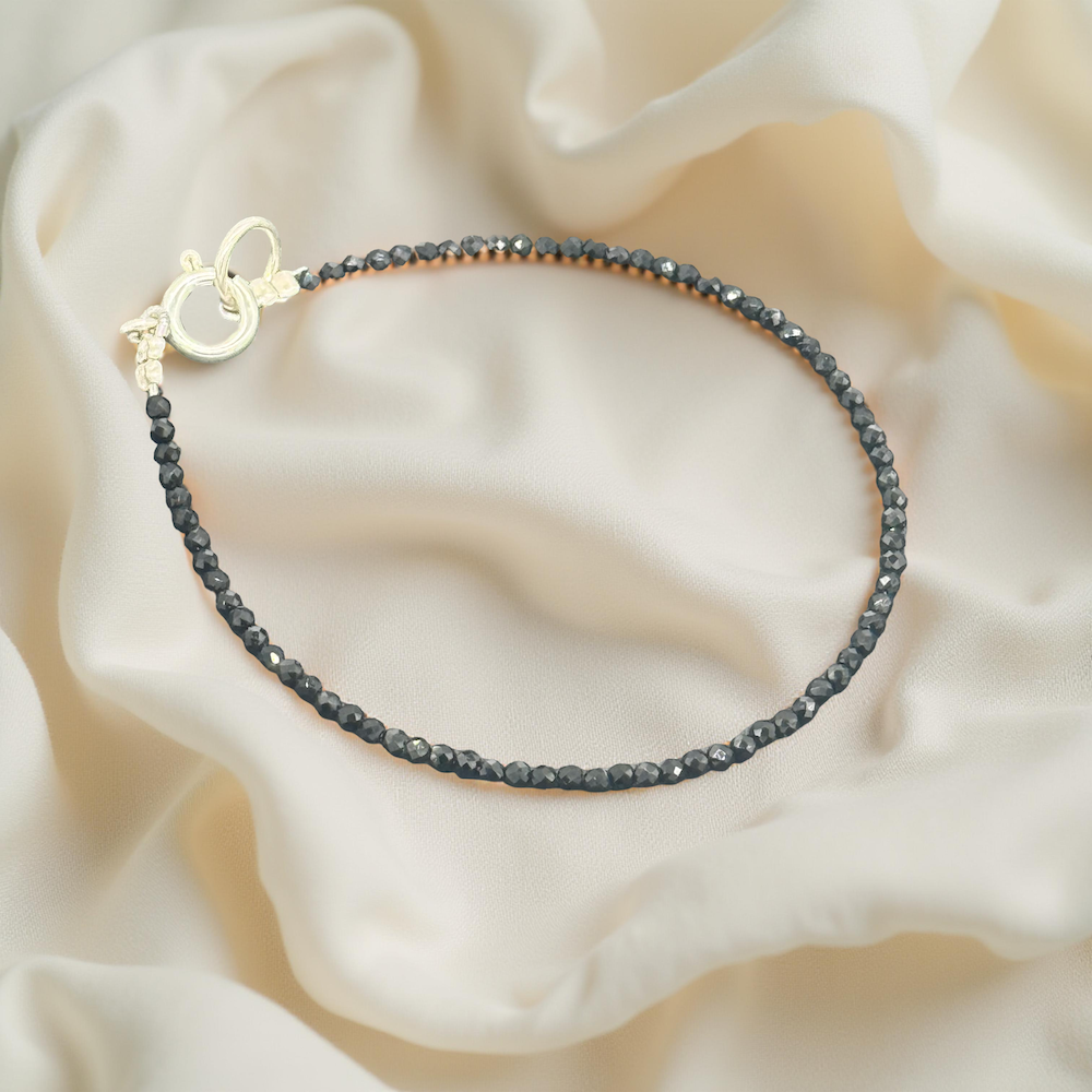 Schwarz-Onyx Armband auf glänzendem, cremigem Seidenstoff