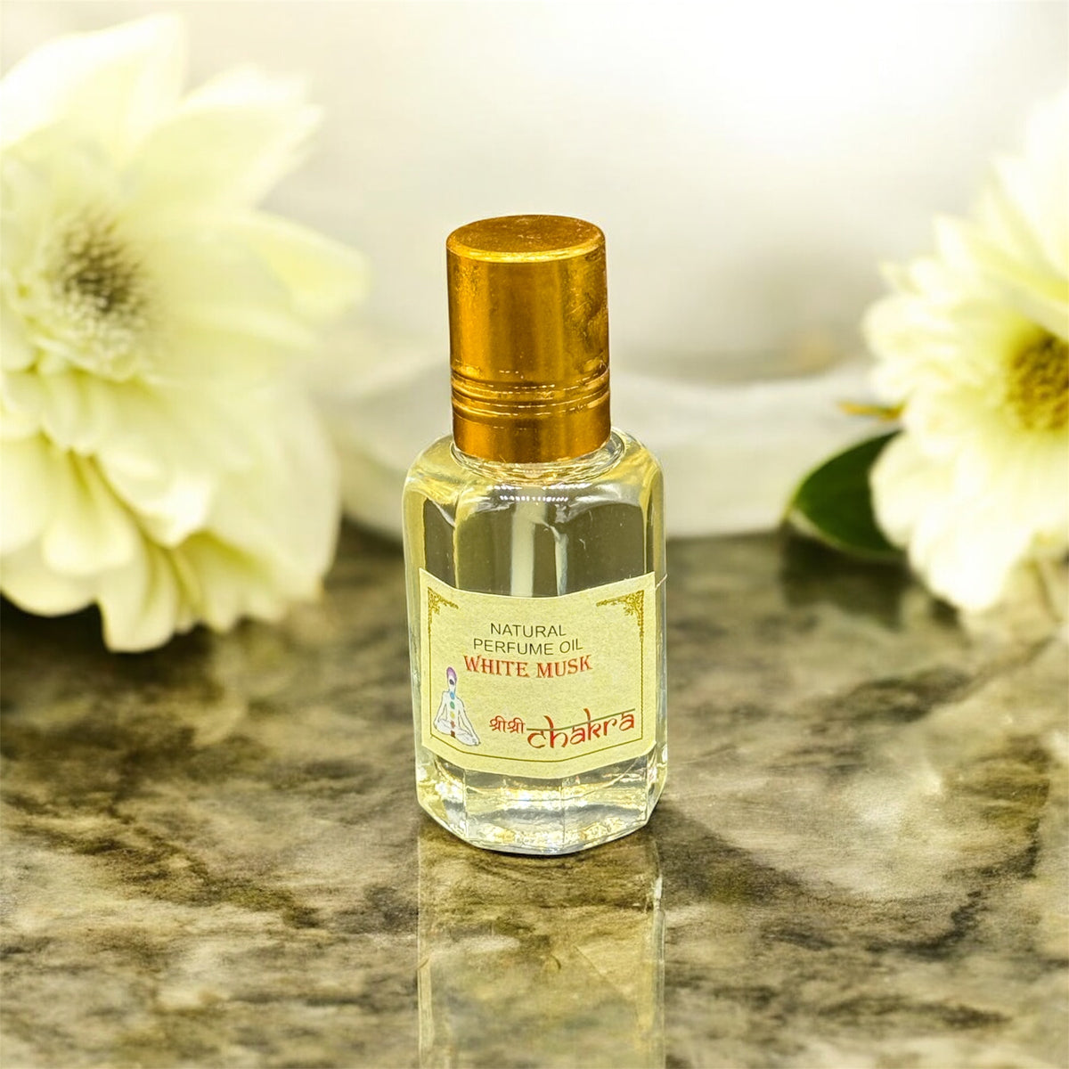Zeigt Ölparfum aus weisser Moschus auf einer Marmorplatte und im Hintergrund sind weisse Blumen