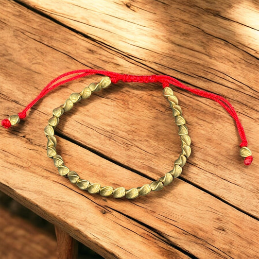 Tibetisches Kupferperlen Armband mit gedrehten Perlen auf rotem Band – Nahaufnahme