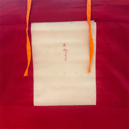 Rückseite des Weisse Tara Thangkas mit roter Stoffeinfassung, heller Bildrückseite, roter Schrift und gelben Bändern