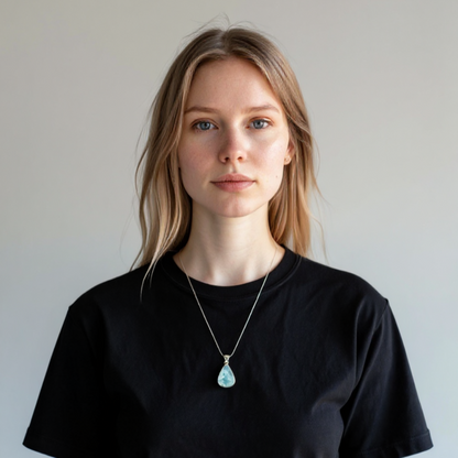 Eine weisse Frau mit schwarzes T-Shirt trägt einen Larimar SIlber-Anhänger im Tropfenform