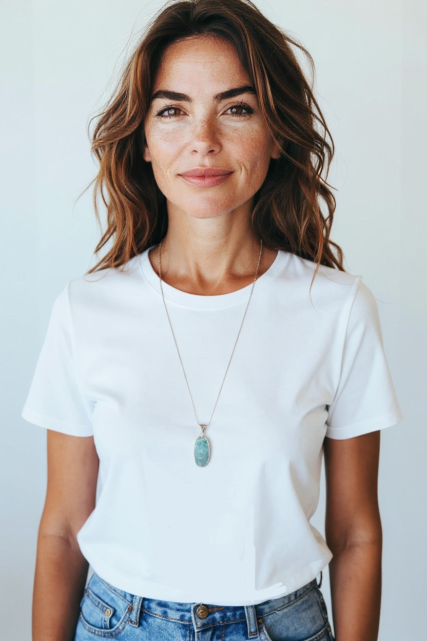 Eine Frau trägt Larimar Silber Anhänger mit einer Silber-Kette. Trägt auch ein weises T-Shirt