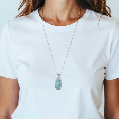 Eine Frau trägt Larimar Silber Anhänger mit einer Silber-Kette. Trägt auch ein weises T-Shirt
