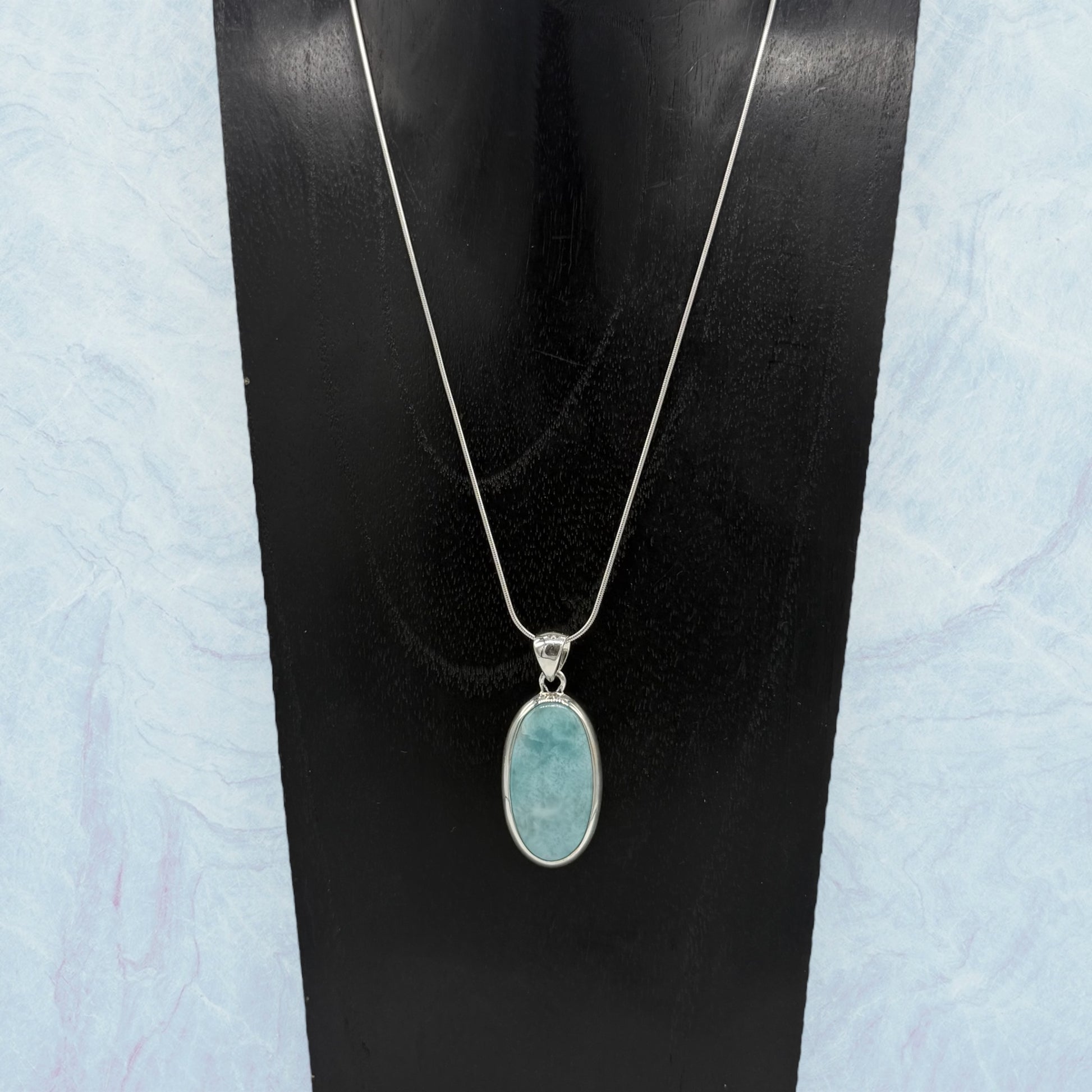 Zeigt Larimar Silber Anhänger mit einer Silber-Kette auf einen Schumckständer