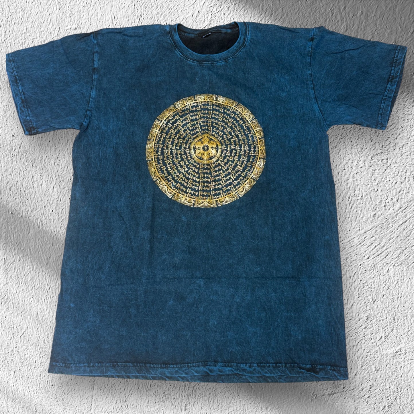Es zeigt ein blaues T-Shirt mit Mandala aus Om Mani Padme Hum Mantra