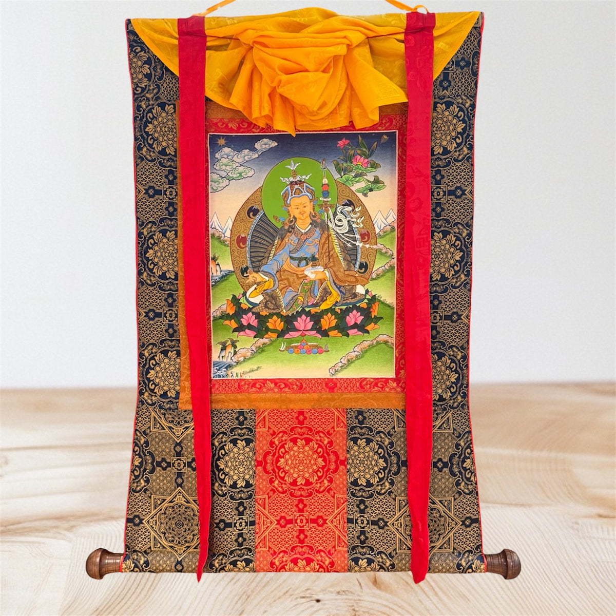 Padmasambhava Thangka mit dunkler goldfarben gemusterter Stoffeinfassung, roten Bändern und gelbem Überwurf, Gesamtansicht
