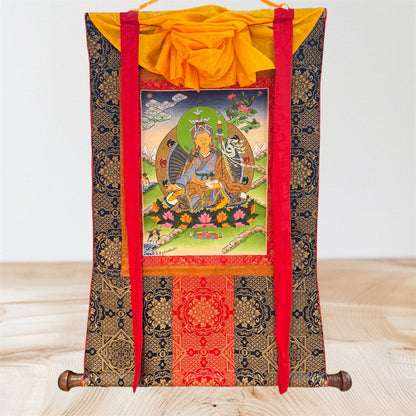 Padmasambhava Thangka mit dunkler goldfarben gemusterter Stoffeinfassung, roten Bändern und gelbem Überwurf, Gesamtansicht