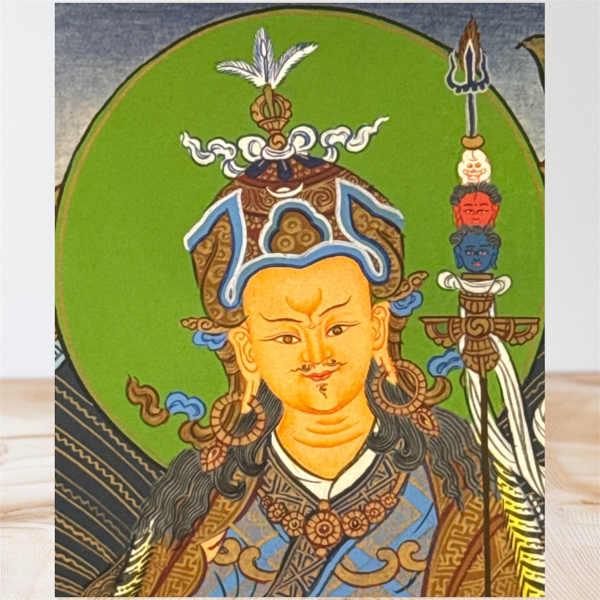 Detail von Padmasambhavas Gesicht und Lotushut vor grünem Heiligenschein, daneben der Khatvanga-Stab
