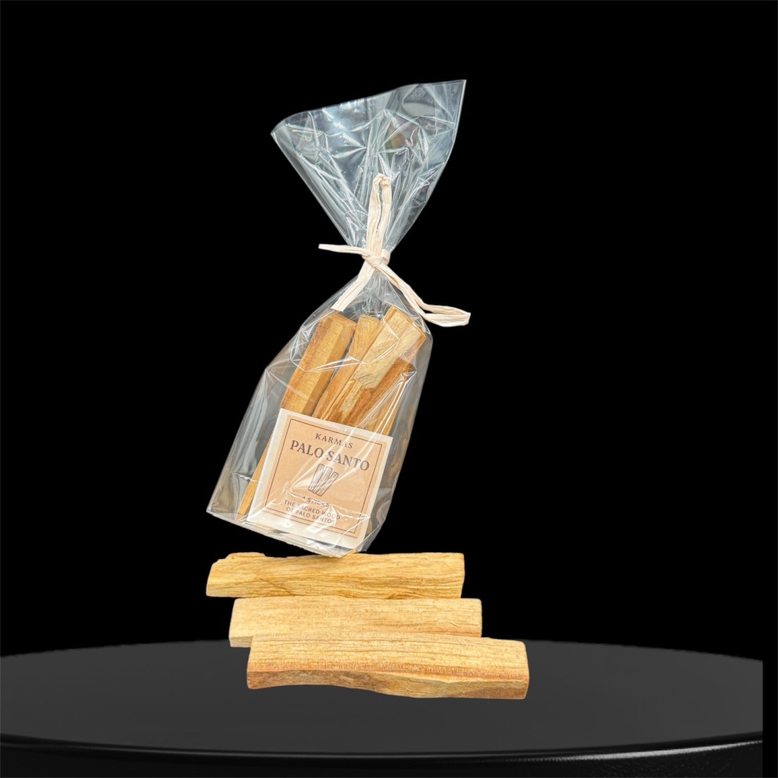 es zeigt 3 Holzstäben liegt offen und eine Plastik-Verpackung  vom Palo-Santo-Räucherstäbchen auf einem schwarze Podium und mit einem schwarzen Hintergrund mit dem Schrift The sacred wood of Palo Santo Incense.