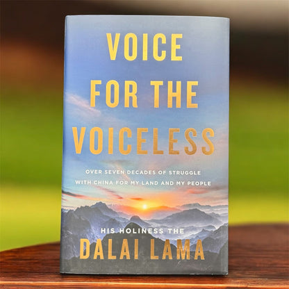 The photo shows a books called the Voice for the Voiceless on a wooden table top and  with a green background.