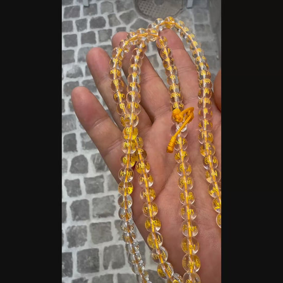 Halten und Zeigen einer Kristall-Mala in der Hand bei Tageslicht.