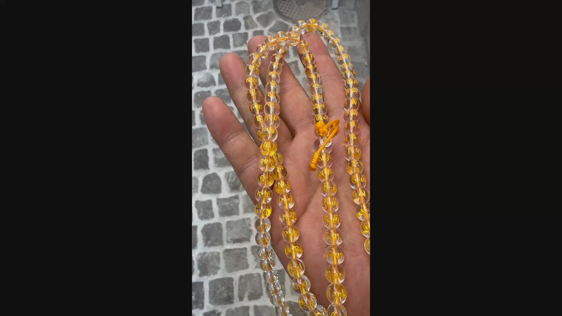 Halten und Zeigen einer Kristall-Mala in der Hand bei Tageslicht.