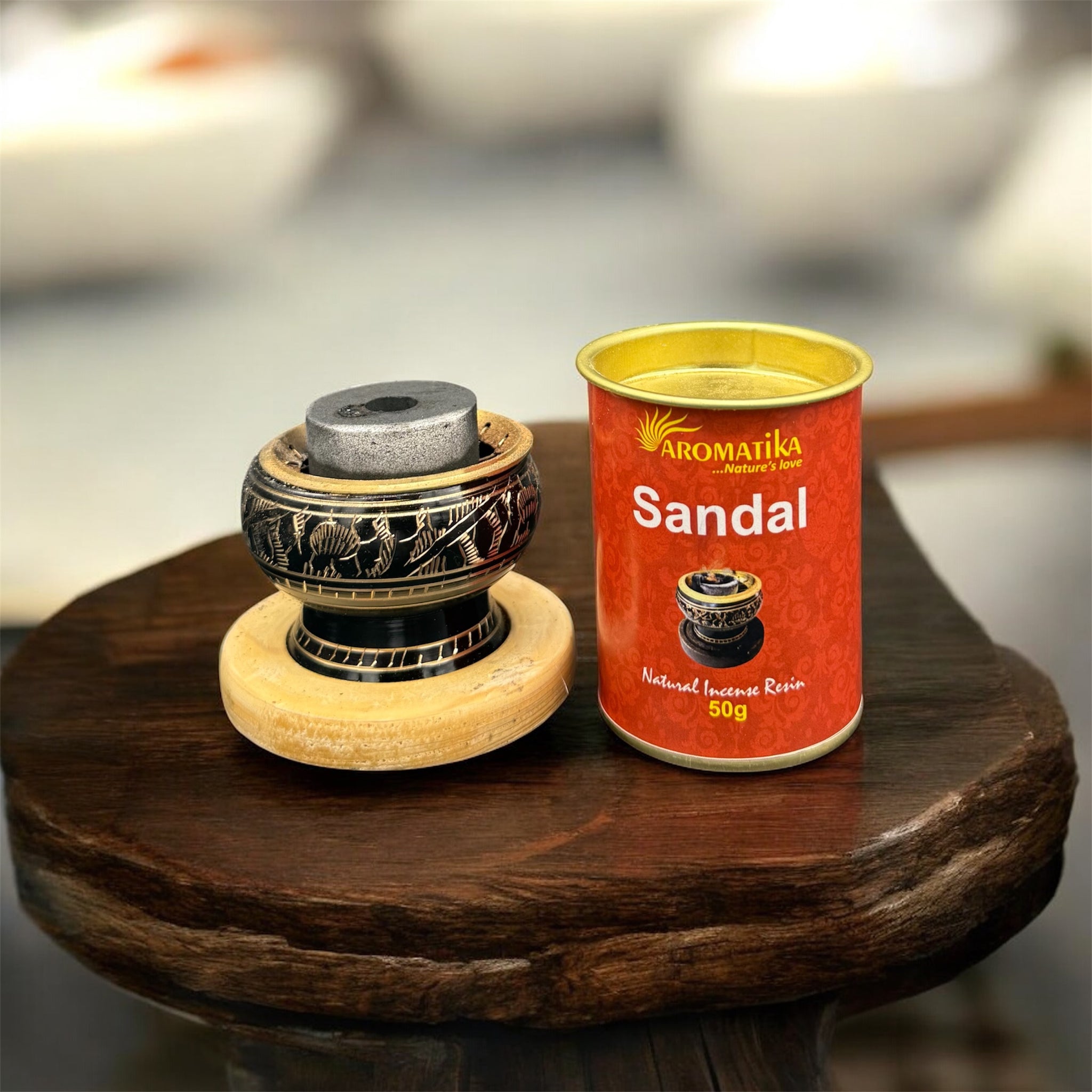 Man sieht brennende Kohle mit Rauch in einem Räuchergefäß aus Metal und  Holz-Untersetzter.